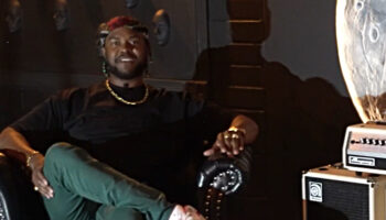 Screenshot from video with Brandon Brown sitting on chair by Ampeg Micro head and cab