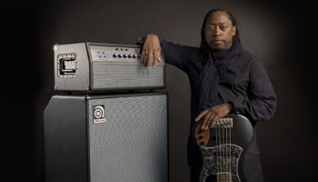 Darryl Jones leaning against an Ampeg stack and upside down bass